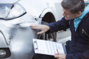 Insurance adjuster inspecting car damaged in accident