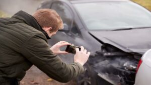 A man taking pictures of a car after an accident.