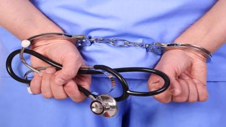 A person in medical scrubs who has been handcuffed.