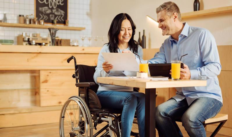 A woman in a wheelchair looking over documents with a man.
