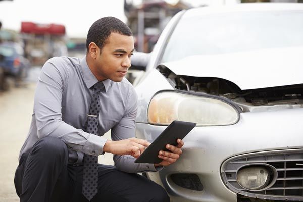 insurance adjuster examines car