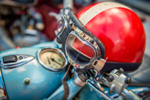Motorcycle Accident Lawyer Gastonia, NC with red helmet resting on blue vintage motorcycle 
