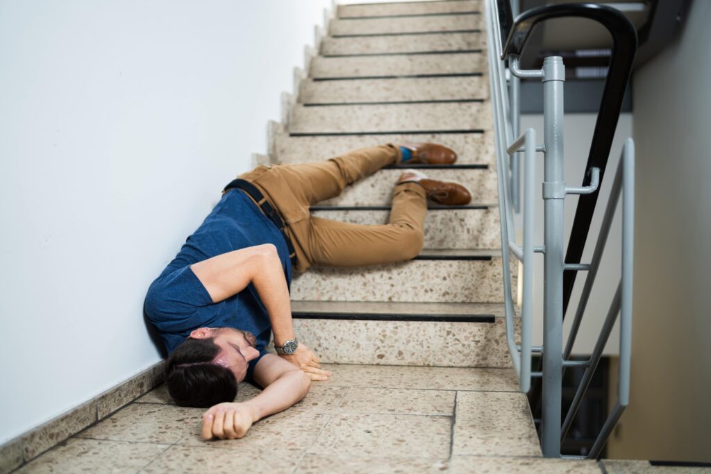 Man with a blue shirt who has fallen down a set of stairs.